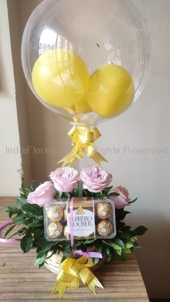Transparent Balloon Bouquet with small yellow balloons inside tied to a box with 6 pink roses and box of 16 ferrero rocher chocolates C-BFST