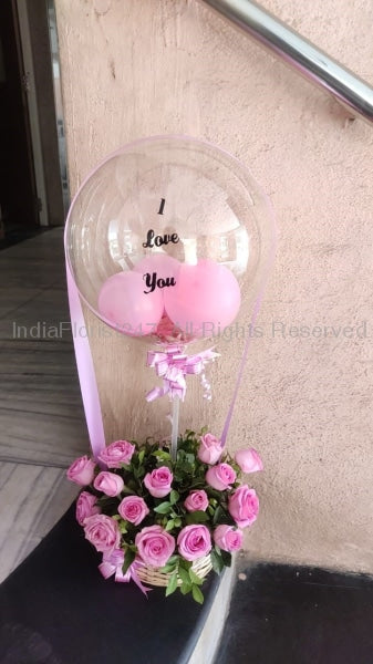 Small Pink balloons in a clear balloon printed I Love You tied to a basket with 10 Pink roses C-BFST
